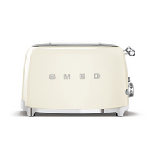 Load image into Gallery viewer, Front View. White Background. Smeg 50's Retro Cream 4 Slice Toaster. The body of the toaster is Cream with chrome letters S, M, E and G embossed on either side. The top, base, levers, knobs and buttons are all chrome. There are two push down levers, two browning knobs, two defrost, two reheat and two stop buttons. One for each set of 2 slots.