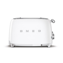 Load image into Gallery viewer, Front View. White Background. Smeg 50's Retro White 4 Slice Toaster. The body of the toaster is white with chrome letters S, M, E and G embossed on either side. The top, base, levers, knobs and buttons are all chrome. There are two push down levers, two browning knobs, two defrost, two reheat and two stop buttons. One for each set of 2 slots.