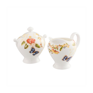 White Background. Aynsley Cottage Garden Cream Jug and Covered Sugar Bowl Set. White Fine porcelain with a rose, leaf and butterfly pattern. The sugar bowl has 2 lug handles.