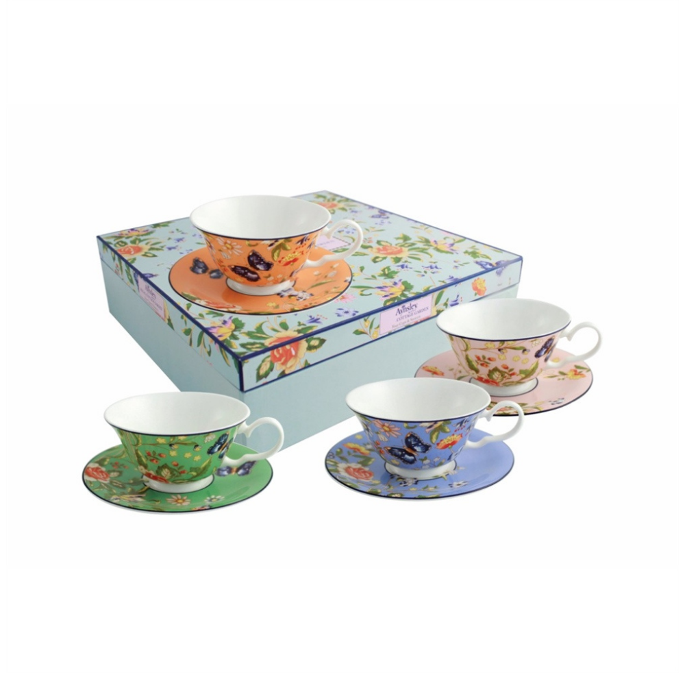 White Background. 4 different coloured teacups and matching saucers sitting on and around their decorative gift box. 1 coral, 1 pink, 1 green and 1 blue. All the cups, saucers and the gift box have an all over floral and butterfly pattern. The cups are white on the inside.