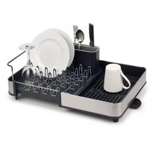 Load image into Gallery viewer, A Grey and Stainless Steel rectangular, expandable dish rack with cutlery hold. The picture shows how it can hold mugs, plates, glasses and cutlery. It also has a draining spout to easily drain away excess water.
