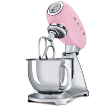 Load image into Gallery viewer, White Background. Smeg 50s Retro Stand Mixer. The top of the mixer is Pink, the base is silver. There are the letters S, M, E and G embossed in chrome on either side of the machine. It has a Stainless Steel 4.8L bowl and beaters. The speed control is a chrome level on the top of the machine. The top lifts up by pressing in a button at the back of the motor case.
