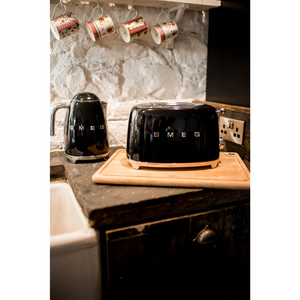 Lifestyle image in a kitchen with Black Smeg 50's Retro Kettle and 2 slice Toaster. There are 4 Julie Dodsworth mugs hanging from a shelf above the set. 