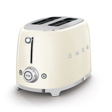 Load image into Gallery viewer, White Background. Cream Smeg Retro 50&#39;s style 2 slicer toaster. It has a cream body, Chrome top and base with chrome embossed letters S M E and G across the front. The push down lever, browning knob, defrost, reheat and stop buttons are all chrome.

