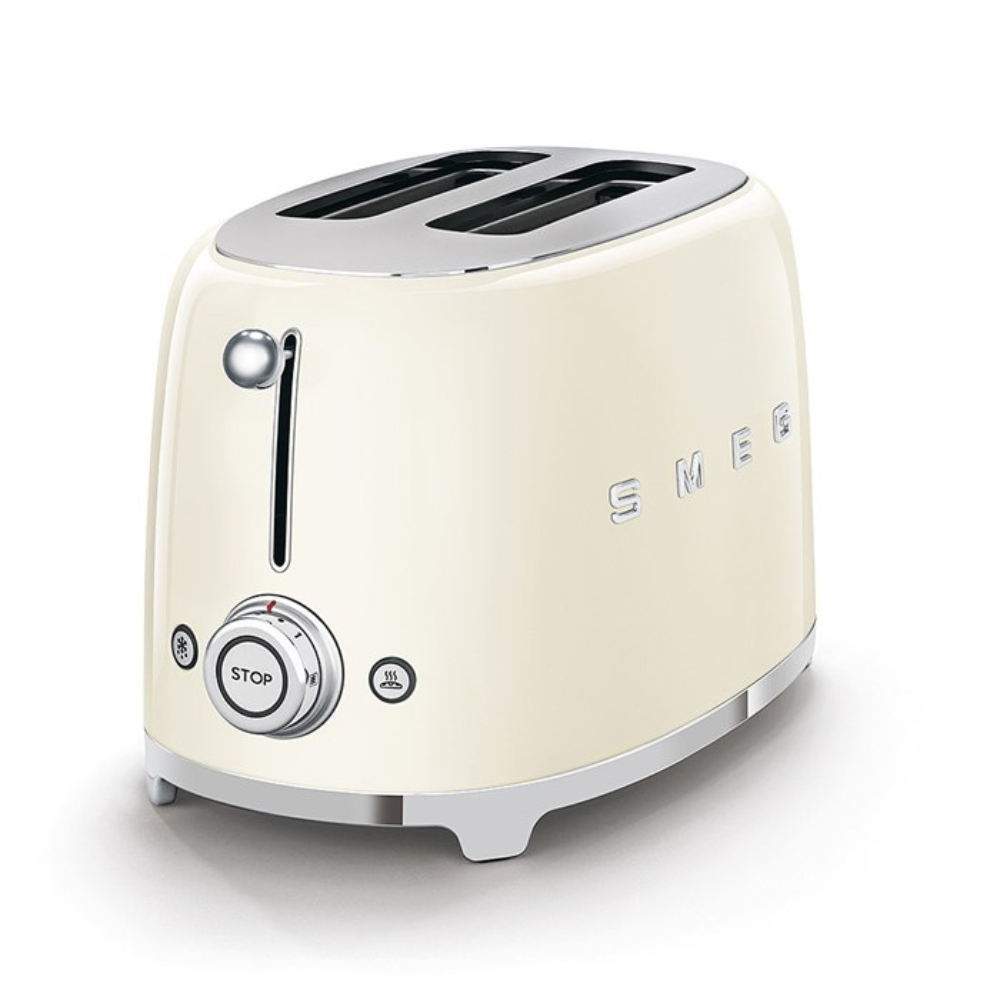 White Background. Cream Smeg Retro 50's style 2 slicer toaster. It has a cream body, Chrome top and base with chrome embossed letters S M E and G across the front. The push down lever, browning knob, defrost, reheat and stop buttons are all chrome.