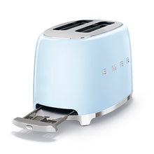 Load image into Gallery viewer, A side view with the crumb tray pulled out from the bottom, at the opposite side of the toaster from the push down lever. White Background. Smeg 2 slice 50&#39;s retro toaster. The body is Pastel blue and it is chrome at the top and bottom. There are chrome S M E and G letters embossed on the front and back. The push down leaver, browning knob, defrost, reheat and stop buttons are all chrome.
