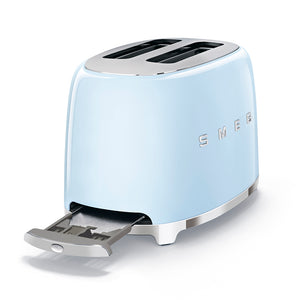 A side view with the crumb tray pulled out from the bottom, at the opposite side of the toaster from the push down lever. White Background. Smeg 2 slice 50's retro toaster. The body is Pastel blue and it is chrome at the top and bottom. There are chrome S M E and G letters embossed on the front and back. The push down leaver, browning knob, defrost, reheat and stop buttons are all chrome.