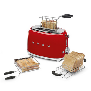 Lifestyle view. White Background. Smeg Red 50s Retro 2 Slice Toaster. The body of the toaster is red with chrome letters S, M, E and G embossed on both sides. The top and base are chrome. The push down lever, defrost, reheat, stop buttons and browning knob are all chrome. This picture shows the accessories available to purchase separately. A Toastie maker and a toast rack. These are filled with toasted wholemeal bread to demonstrate their purpose.