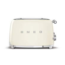 Load image into Gallery viewer, Front View. White Background. Smeg 50&#39;s Retro Cream 4 Slice Toaster. The body of the toaster is Cream with chrome letters S, M, E and G embossed on either side. The top, base, levers, knobs and buttons are all chrome. There are two push down levers, two browning knobs, two defrost, two reheat and two stop buttons. One for each set of 2 slots.
