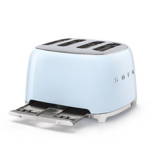 Load image into Gallery viewer, Side View With Crumb trays pulled out. White Background. Smeg 50&#39;s Retro Pastel Blue 4 Slice Toaster. The body of the toaster is Pastel Blue with chrome letters S, M, E and G embossed on either side. The top, base, levers, knobs and buttons are all chrome. There are two push down levers, two browning knobs, two defrost, two reheat and two stop buttons. One for each set of 2 slots.
