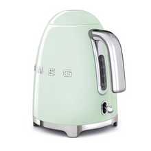Load image into Gallery viewer, Rear Side View. White Background. Smeg 50s Retro 1.7L Kettle. The body of the kettle is Pastel Green. There are chrome letters S, M, E and G embossed on each side. The lid is push button release. The spout, Handle, on/off lever and base are chrome. There is a water level window in line with the handle.
