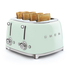 Load image into Gallery viewer, White Background. Smeg 50&#39;s Retro Pastel Green 4 Slice Toaster. The body of the toaster is Pastel Green with chrome letters S, M, E and G embossed on either side. The top, base, levers, knobs and buttons are all chrome. There are two push down levers, two browning knobs, two defrost, two reheat and two stop buttons. One for each set of 2 slots. There are pieces of toasted wholemeal bread sitting up from each slot.
