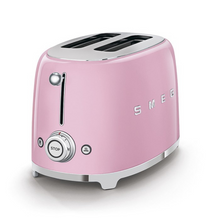 Load image into Gallery viewer, White Background. Smeg Pink 50s Retro 2 Slice Toaster. The body of the toaster is pink with chrome letters S, M, E and G embossed on both sides. The top and base are chrome. The push down lever, defrost, reheat, stop buttons and browning knob are all chrome.
