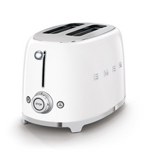 Load image into Gallery viewer, White Background. Smeg White 50s Retro 2 Slice Toaster. The body of the toaster is white with chrome letters S, M, E and G embossed on both sides. The top and base are chrome. The push down lever, defrost, reheat, stop buttons and browning knob are all chrome.
